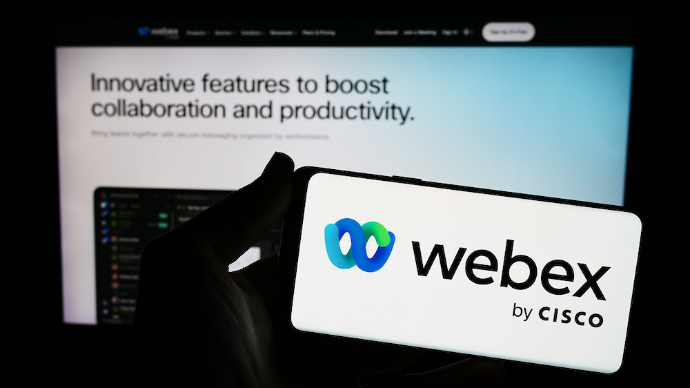 Person holding smartphone with logo of US unified communications company Webex by Cisco in front of website. 