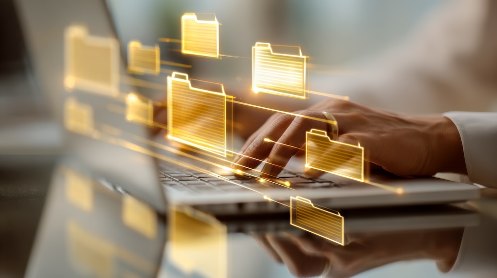 An individual expertly handles digital data with vibrant holographic folders hovering over their sleek laptop in a contemporary workspace, embodying efficiency and innova