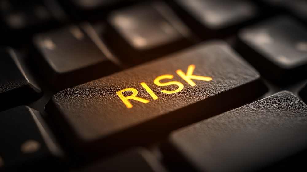 A close-up of a keyboard key labeled RISK, illuminated in orange, emphasizing the concept of risk in a digital context.