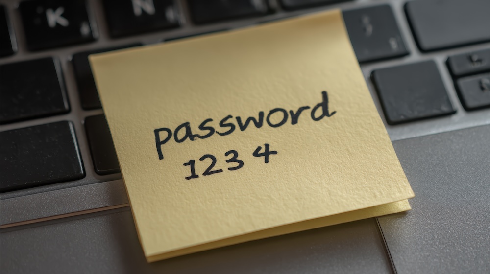 Sticky note showing weak password on laptop keyboard representing cybersecurity compliance risks